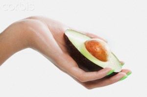 Woman holding sliced avocado